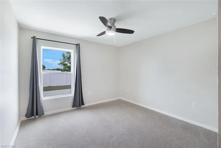 Unfurnished room featuring ceiling fan and light carpet