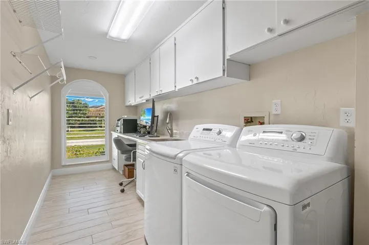 Laundry room with cabinet space, wood tiled floors, an office area, and washer and dryer