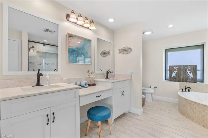 Bathroom featuring double vanity, a shower stall, a bath, light wood-style flooring, and recessed lighting