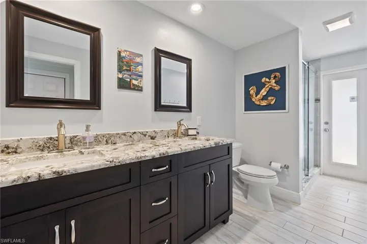Full bath featuring double vanity, a stall shower, and wood tiled floors