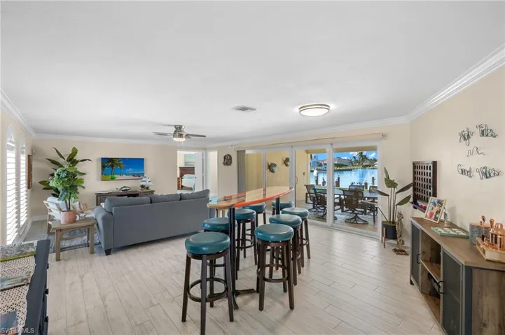 Dining room with ceiling fan, light wood finished floors, crown molding, and plenty of natural light