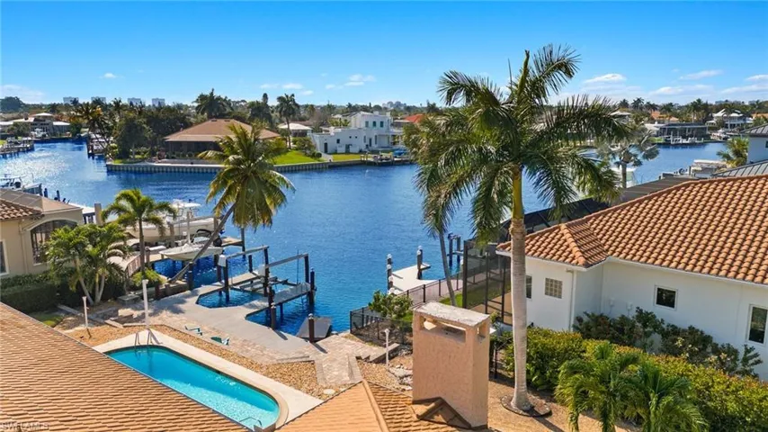 Dock area featuring boat lift, an outdoor pool, a water view, a residential view, and a patio