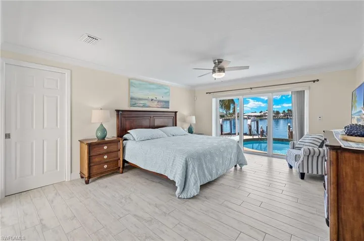 Bedroom featuring crown molding, a water view, ceiling fan, access to exterior, and light wood finished floors