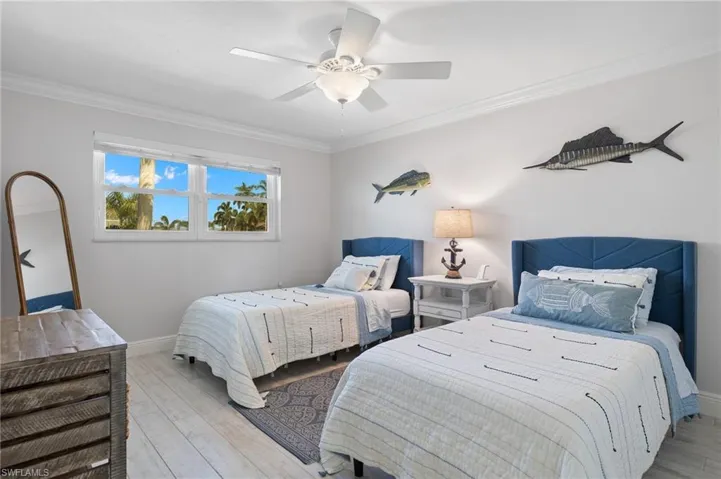 Bedroom featuring ornamental molding, wood finished floors, and a ceiling fan