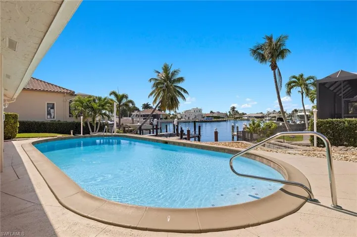 Outdoor pool with a dock, boat lift, a patio area, and a residential view