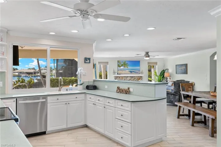 Kitchen with dishwasher, white cabinets, a peninsula, ceiling fan, and ornamental molding