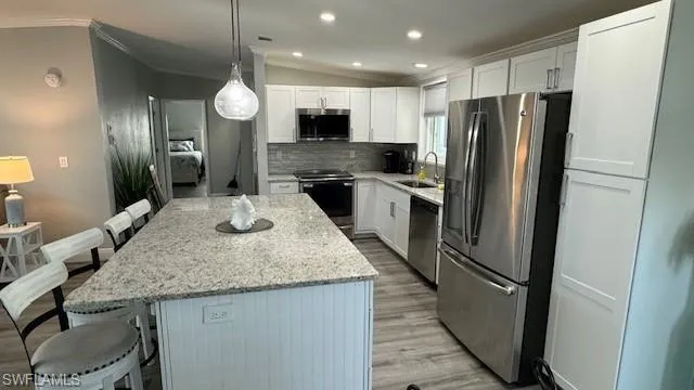 Kitchen with tasteful backsplash, a kitchen island, appliances with stainless steel finishes, and pendant lighting