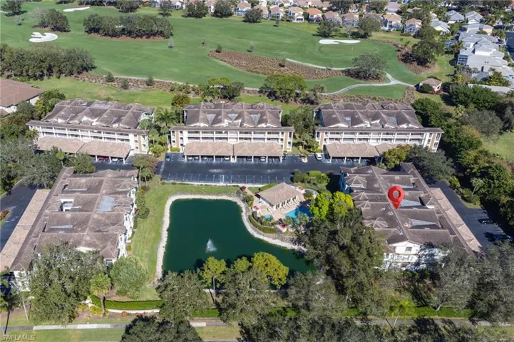 Aerial view of property and surrounding area with a golf course, a large body of water, and nearby suburban area