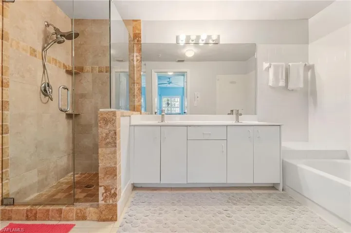 Full bath with double vanity, a stall shower, light tile patterned floors, and a bath