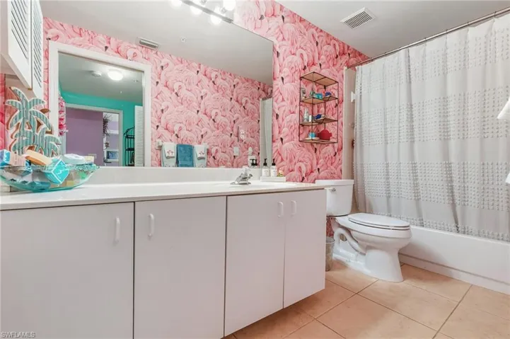 Full bathroom featuring wallpapered walls, vanity, light tile patterned floors, and shower / bath combo with shower curtain