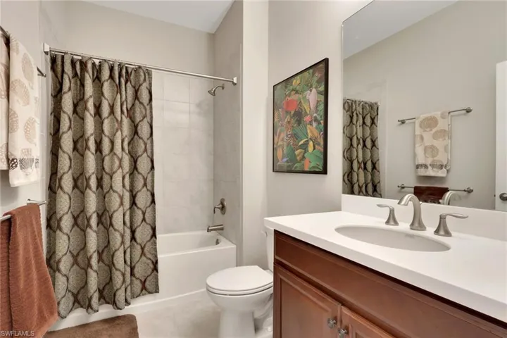 Bathroom with shower / bathtub combination with curtain, vanity, and light tile patterned flooring