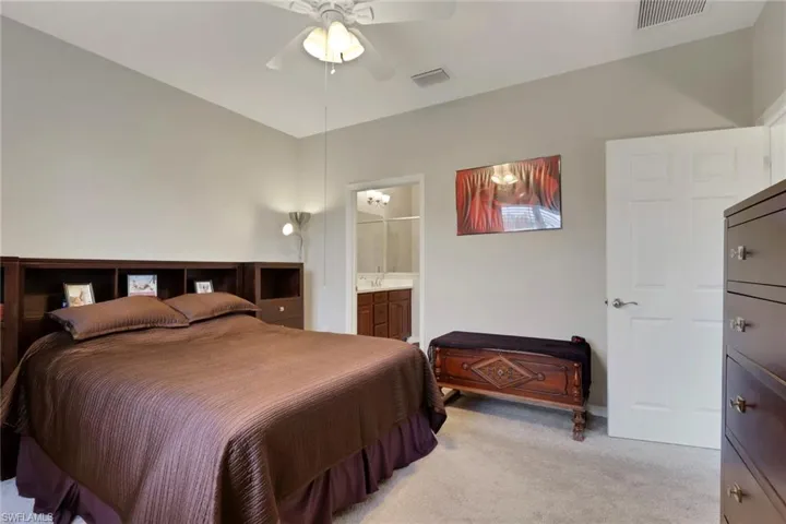 Bedroom featuring light colored carpet, a ceiling fan, and ensuite bathroom