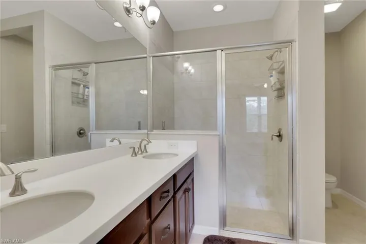 Full bathroom with double vanity, a shower stall, and light tile patterned flooring