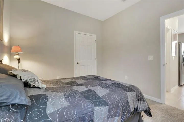 Bedroom featuring light carpet and stainless steel refrigerator with ice dispenser
