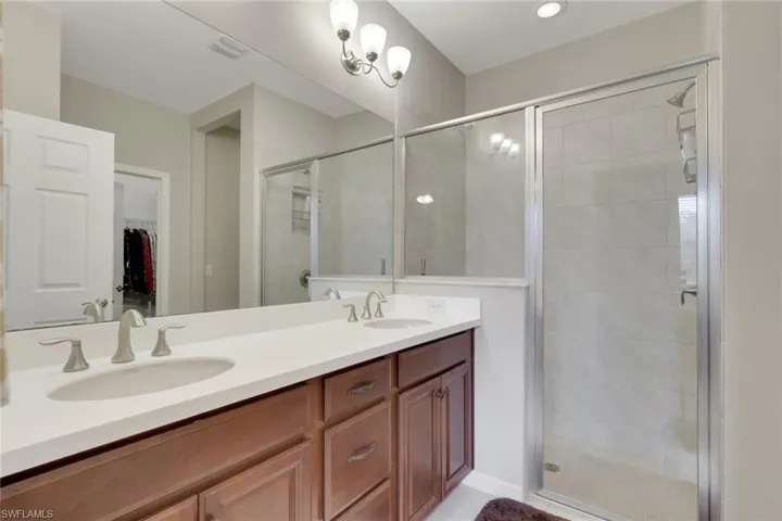 Bathroom with double vanity, a walk in closet, and a shower stall
