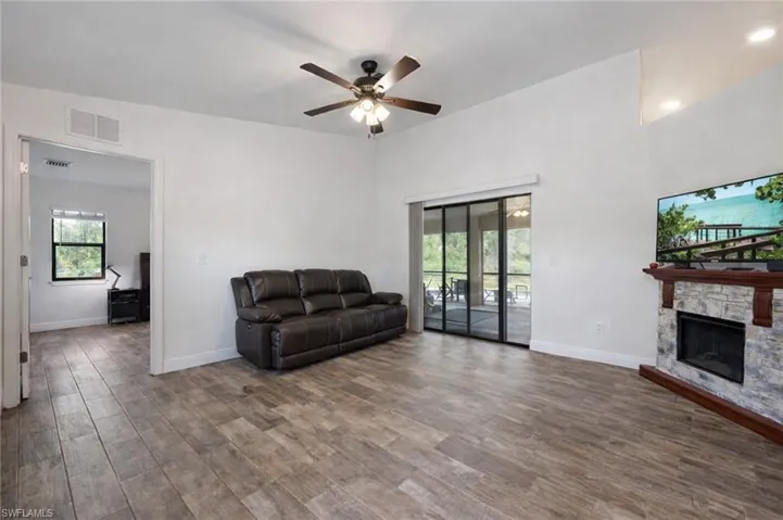 Living room featuring a fireplace, a ceiling fan, and dark wood-style flooring