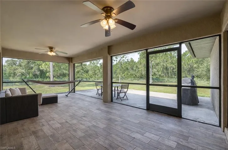 Unfurnished sunroom featuring ceiling fan and view of scattered trees