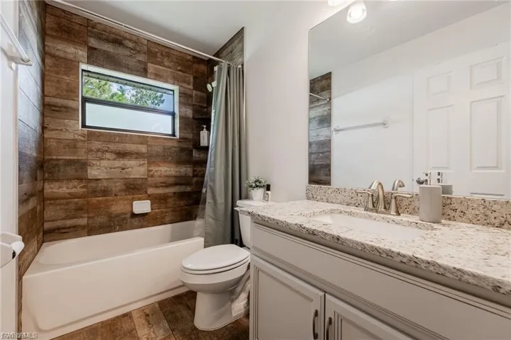 Bathroom with vanity, dark wood-style flooring, and shower / tub combo