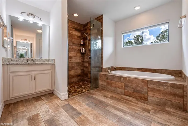 Full bathroom featuring vanity, a bath, a tile shower, light wood-style floors, and recessed lighting