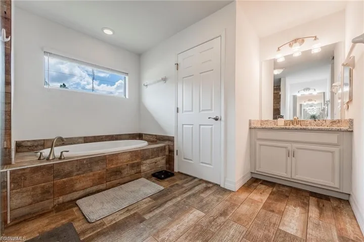 Full bathroom featuring vanity, a bath, and light wood finished floors