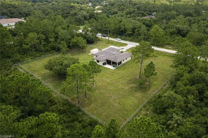 Aerial view of property and surrounding area with a heavily wooded area