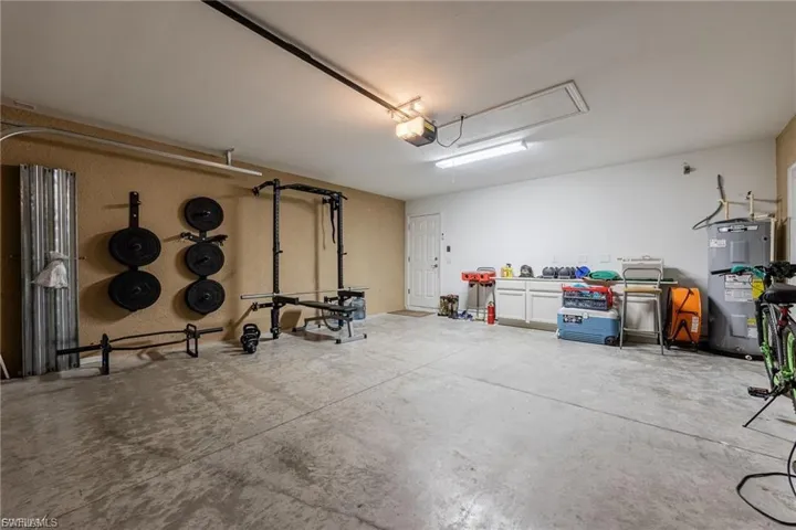 Garage featuring electric water heater and a garage door opener