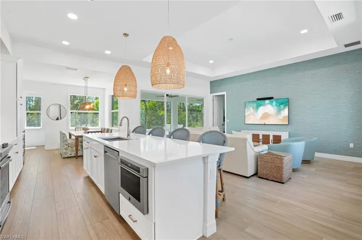 Kitchen with wallpapered walls, appliances with stainless steel finishes, a raised ceiling, and a sink