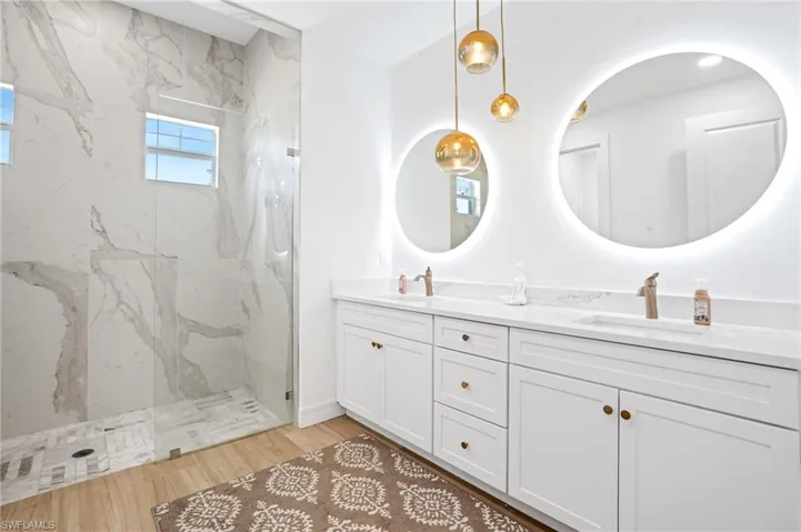 Bathroom featuring double vanity, a marble finish shower, and a sink