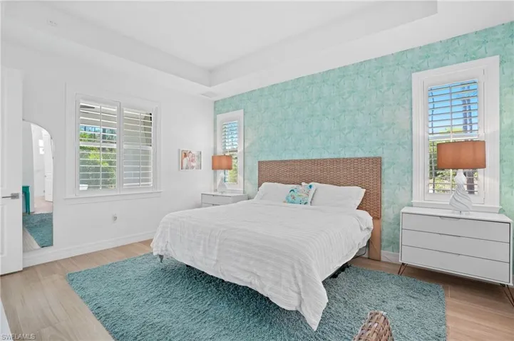 Bedroom with arched walkways, multiple windows, and baseboards