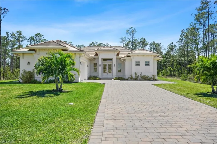 View of front of home featuring an attached garage, a tiled roof, decorative driveway, and a front yard
