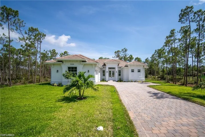 Mediterranean / spanish house featuring decorative driveway, a tile roof, stucco siding, a front yard, and a garage