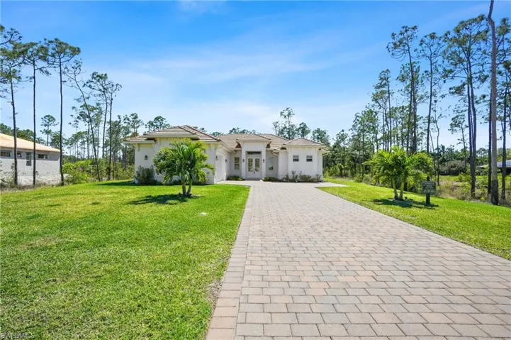View of front of property featuring decorative driveway, a front lawn, and stucco siding