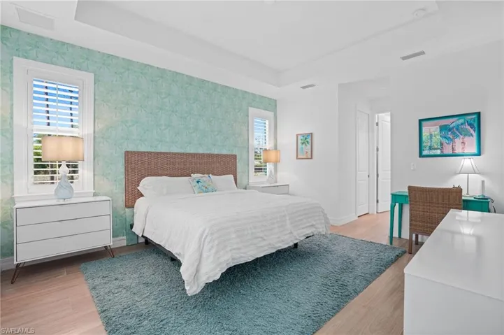 Bedroom featuring a tray ceiling, visible vents, and baseboards
