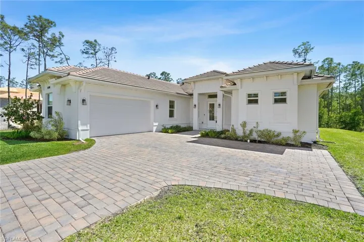 View of front of home with an attached garage, a tile roof, decorative driveway, and stucco siding