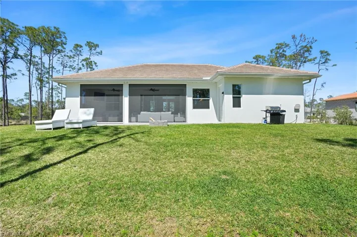 Back of house with ceiling fan, a sunroom, a tiled roof, a lawn, and stucco siding