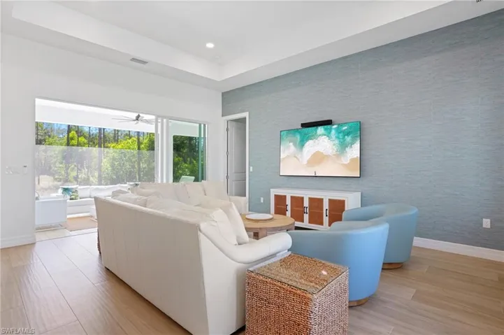 Living room with an accent wall, light wood finished floors, baseboards, and wallpapered walls