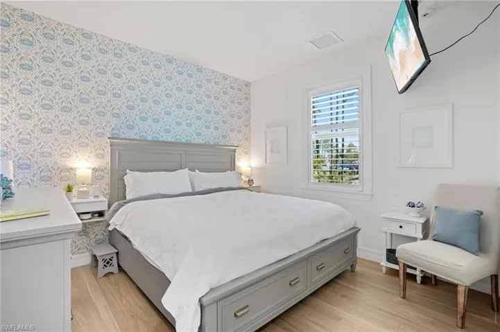 Bedroom with visible vents, light wood finished floors, baseboards, and wallpapered walls