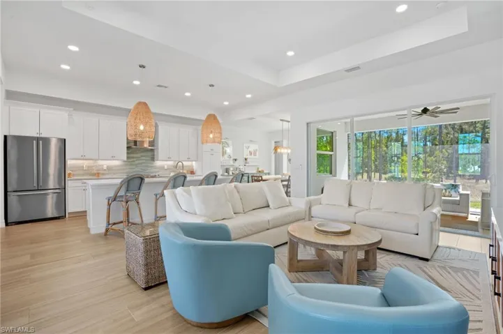 Living room featuring a tray ceiling, light wood-style floors, visible vents, and recessed lighting