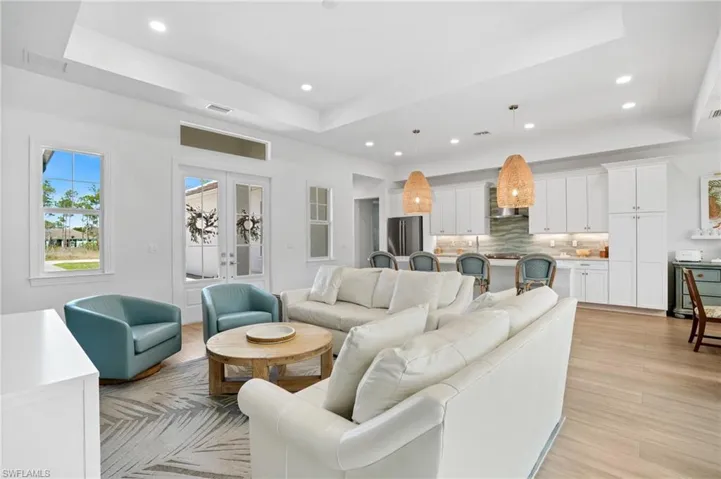 Living area featuring light wood-type flooring, a tray ceiling, french doors, and visible vents