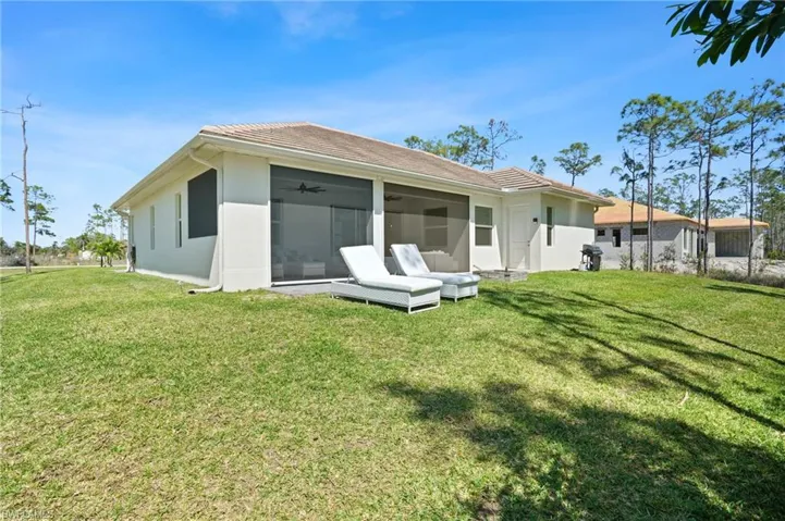 Rear view of property featuring ceiling fan, a lawn, a sunroom, and stucco siding