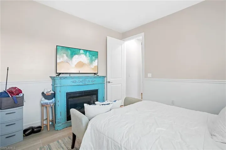 Bedroom featuring wood finished floors and a glass covered fireplace