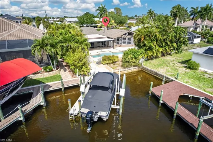 Waterfront property featuring a private boat dock, a boat lift with a red canopy, and direct water access