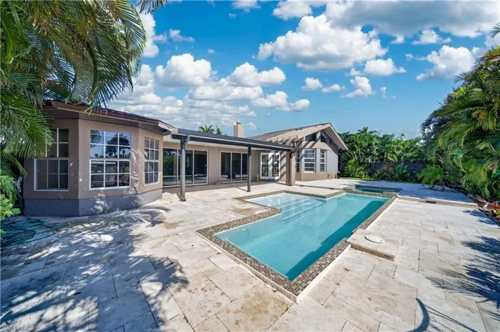 The property features an extensive paved patio area, a swimming pool, and an integrated spa