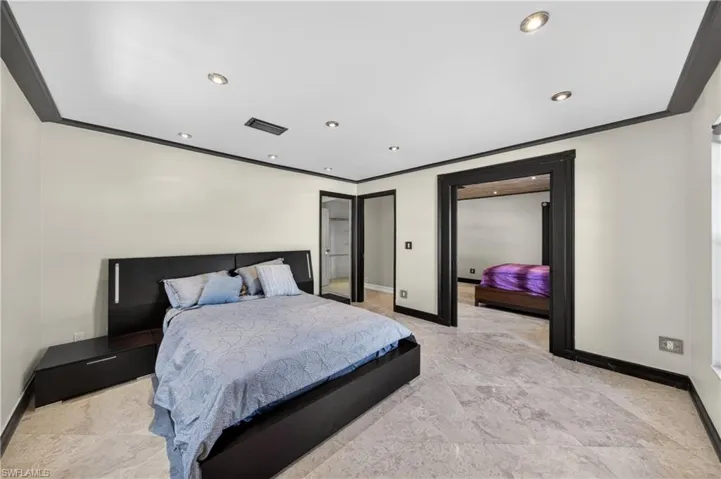 This bedroom features light-colored walls, recessed lighting, and a dark crown molding and trim