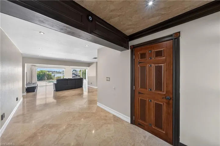 Entryway featuring a decorative wooden door with dark trim, recessed lighting, and polished tile flooring