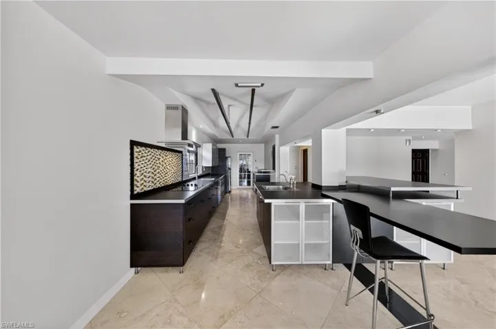 The kitchen features marble flooring, dark cabinetry, and integrated stainless steel appliances