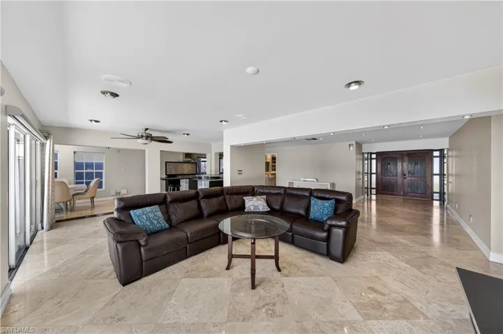 Spacious living area featuring light-colored tile flooring, recessed lighting, and a ceiling fan