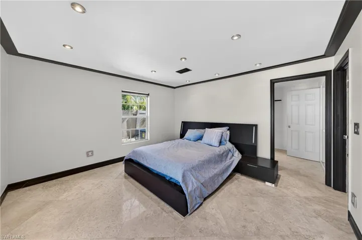Bedroom with light-colored tile flooring, a window providing natural light, and recessed lighting