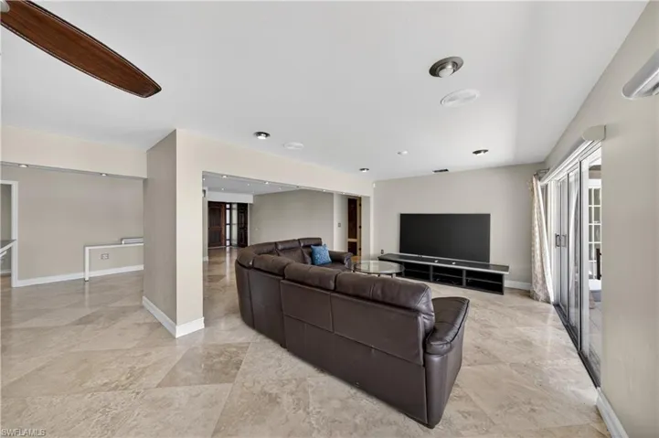 Spacious living area featuring light-toned tile flooring, recessed lighting, and a ceiling fan