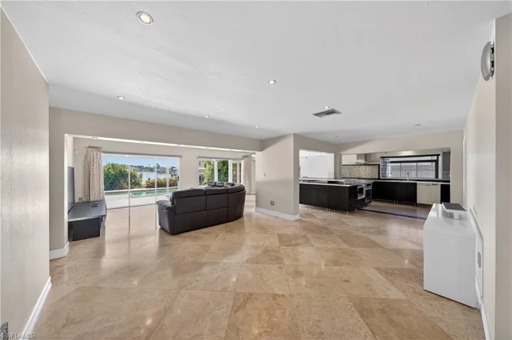 This expansive living area features light-toned tiled flooring and recessed lighting throughout